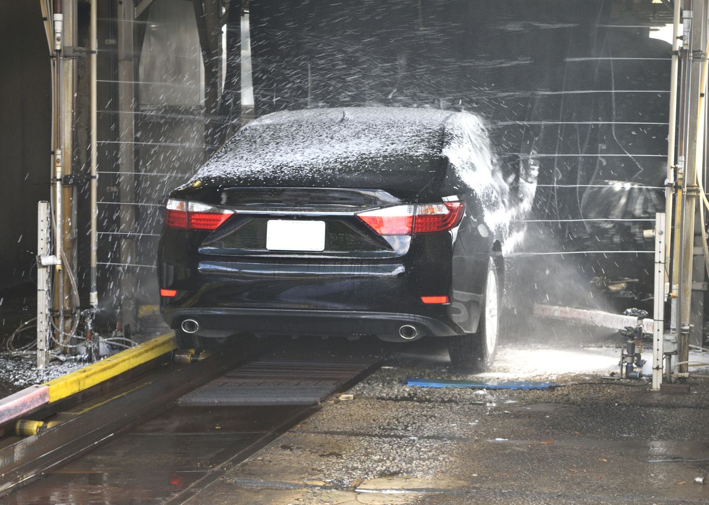 A dark saloon moving through a car wash