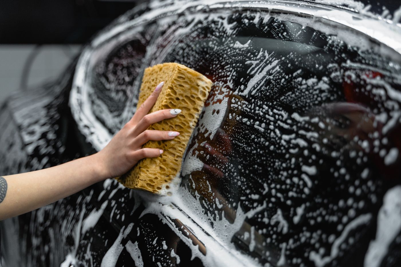 Hand washing soap off a black car with a sponge